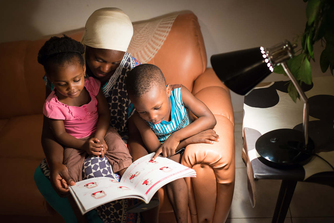 Famille sénégalaise lisant à la lumière électrique