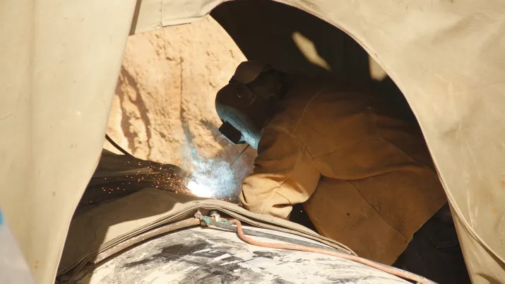 Une personne entrain de souder un immense tuyau pour l'eau