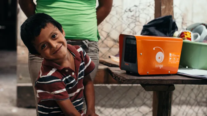 Un enfant souriant à côté d'un boitier Kingo