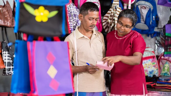Une femme et un homme devant un magasin en trainde regarder un papier