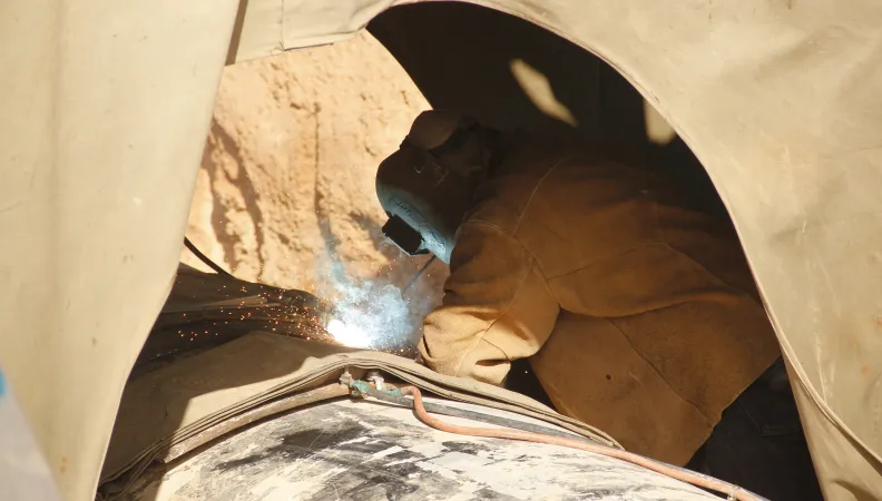 Une personne entrain de souder un immense tuyau pour l'eau