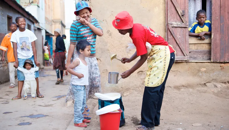 Une femme entrain de servir du lait à un enfant et sa mère