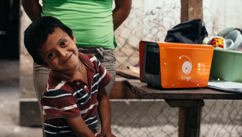 Un enfant souriant à côté d'un boitier Kingo